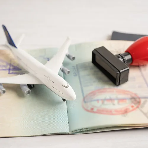 An image depicting an airplane alongside a passport and a stamp on a travel document, illustrating travel as part of the immigration journey.