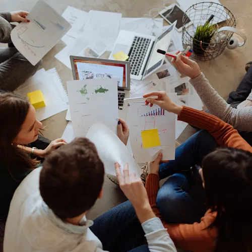 Several people collaborating at a table, surrounded by papers, engaged in a productive conversation.